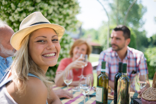 ragazza sorride in compagnia di amici che degustano viono